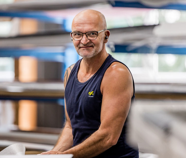 Mitarbeiter in der Produktion von Newo Sonnen- und Insektenschutz Mann mit Brille im Tank-Top in einer Werkstatt